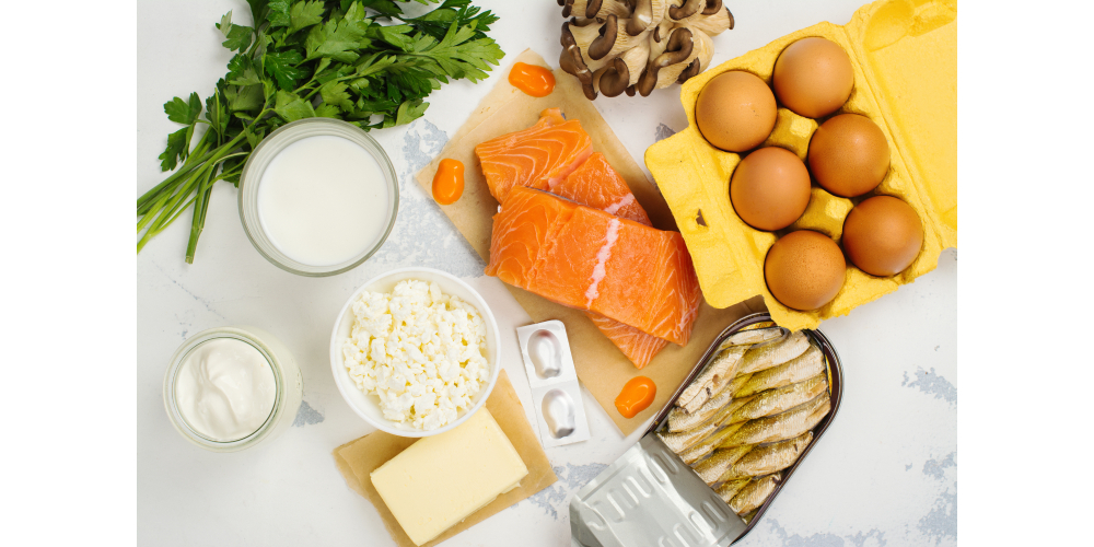 Foods for spinal health with Vitamin D and calcium sources, such as milk, cheese, fish, eggs, and nuts, on a wooden surface.